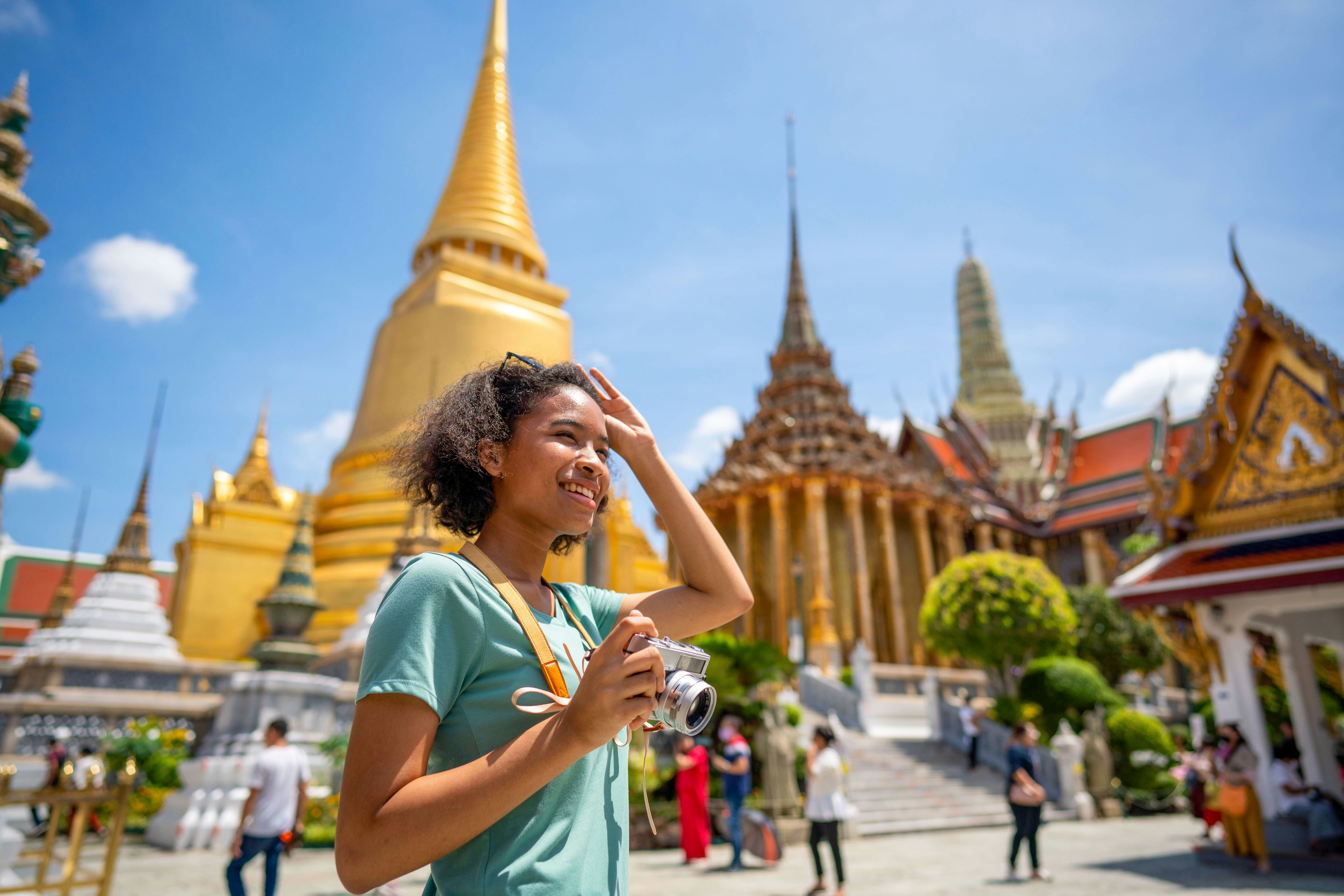 Young woman traveler with backpack traveling into beautiful pagoda in Wat Pra Kaew.